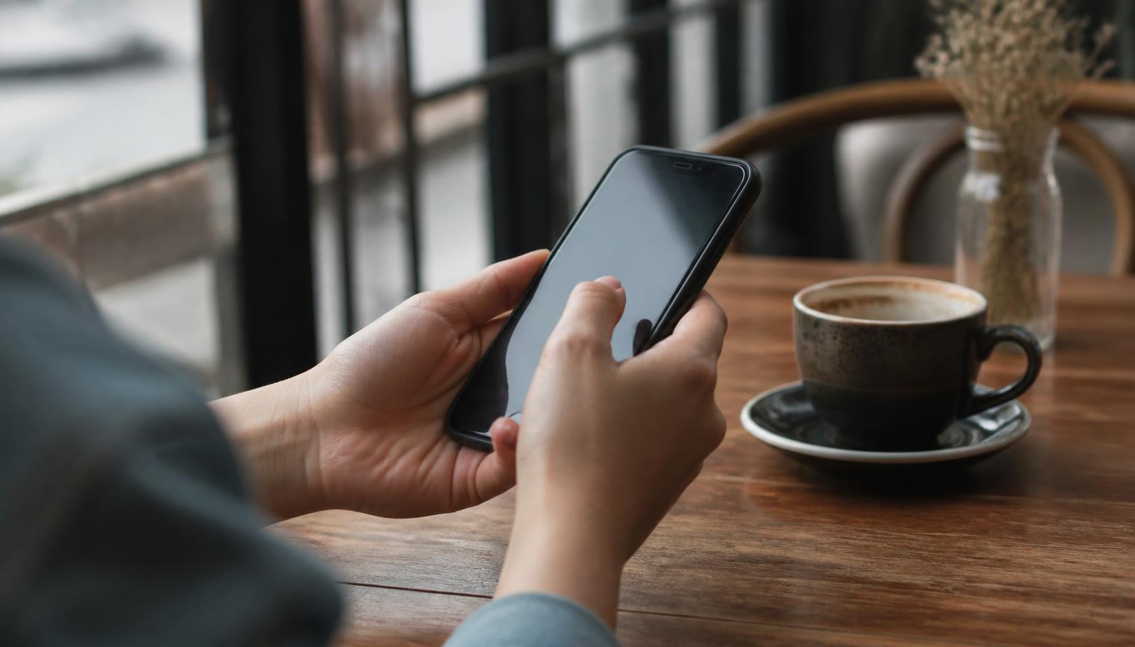 Customer leaving a review on a smartphone at a cafe table